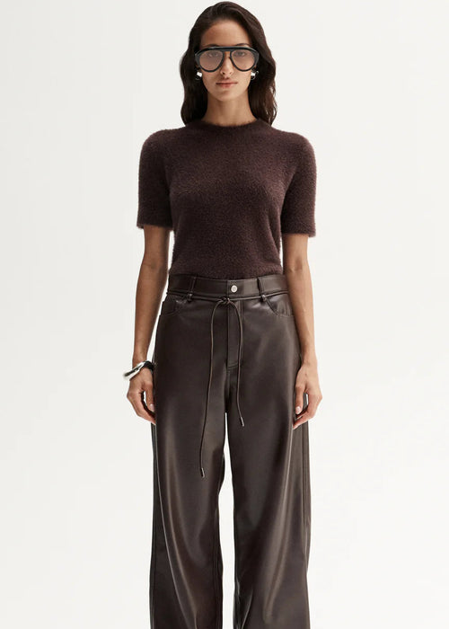 Woman wearing a brown top and wide-leg pants on a white background