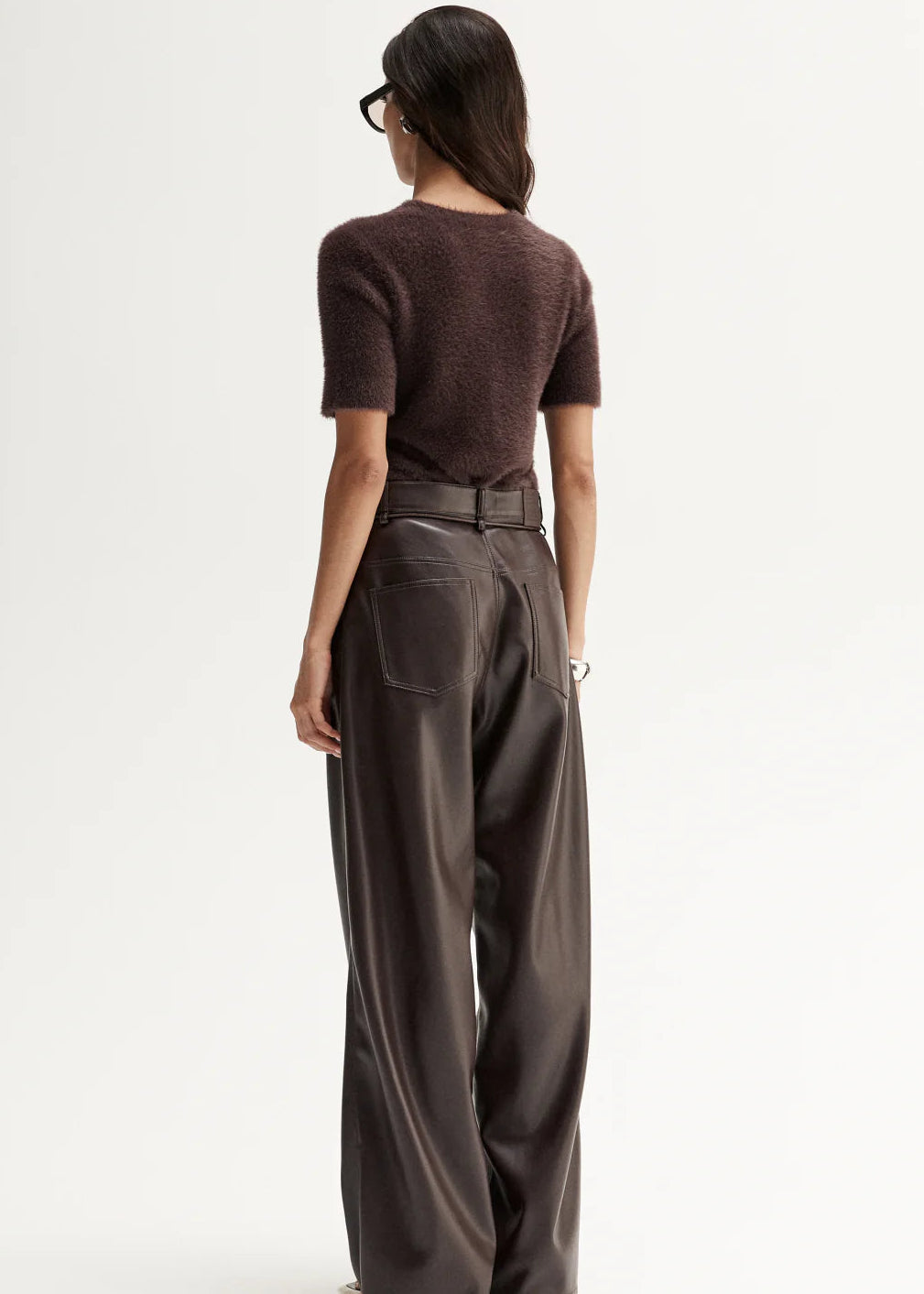 Woman wearing a brown top and wide-leg pants on a white background