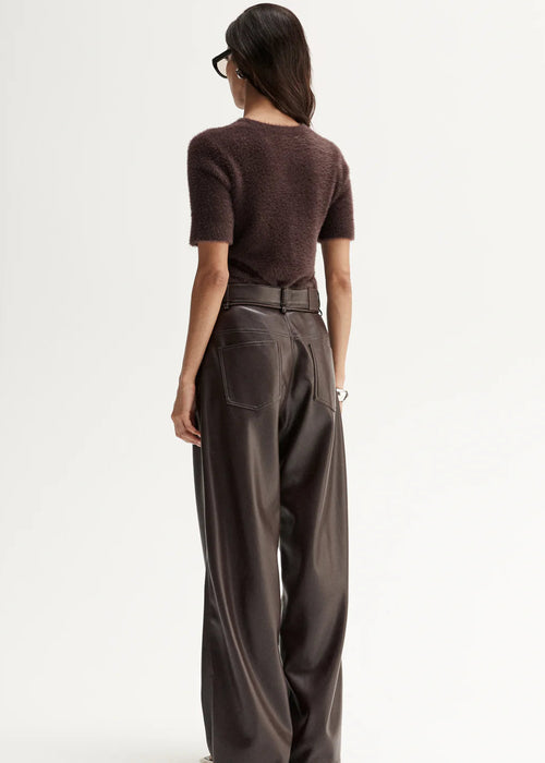 Woman wearing a brown top and wide-leg pants on a white background