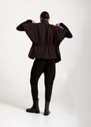Person wearing a dark brown jacket and pants on a white background