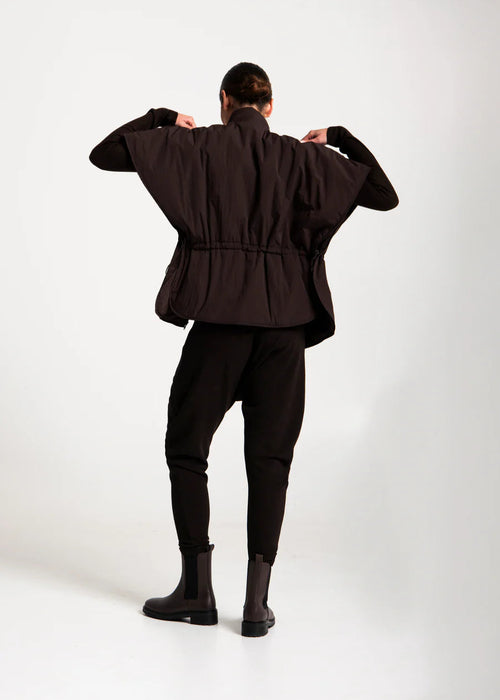 Person wearing a dark brown jacket and pants on a white background