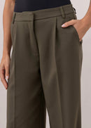 Person wearing olive green wide-leg pants and a black top on a plain background