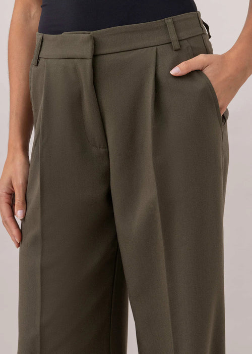 Person wearing olive green wide-leg pants and a black top on a plain background