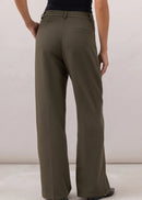 Person wearing olive green wide-leg pants and a black top on a plain background