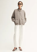 Person wearing a grey jacket and white pants on a white background