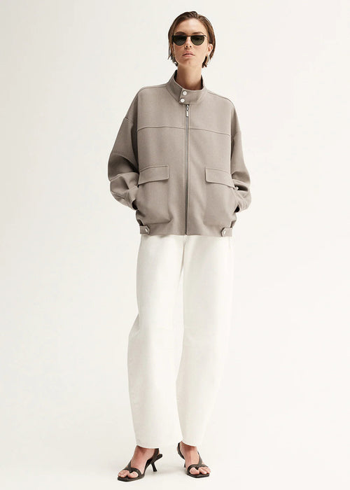 Person wearing a grey jacket and white pants on a white background