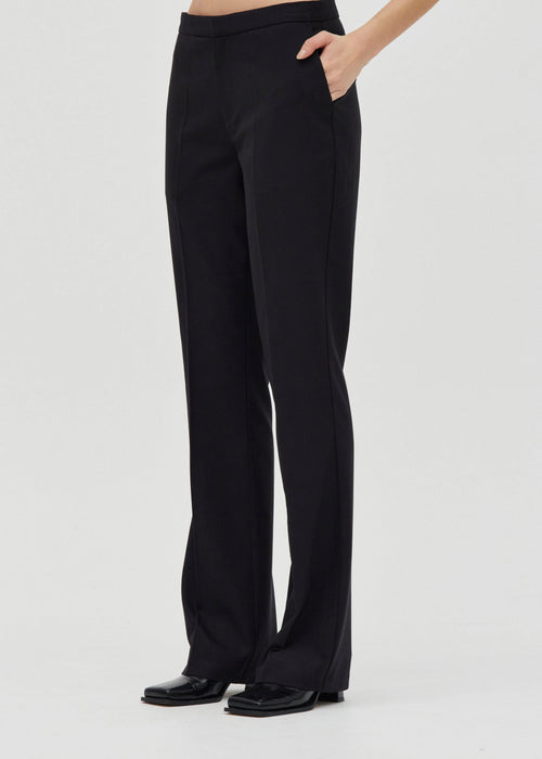 Black pants worn by a person on a light grey background