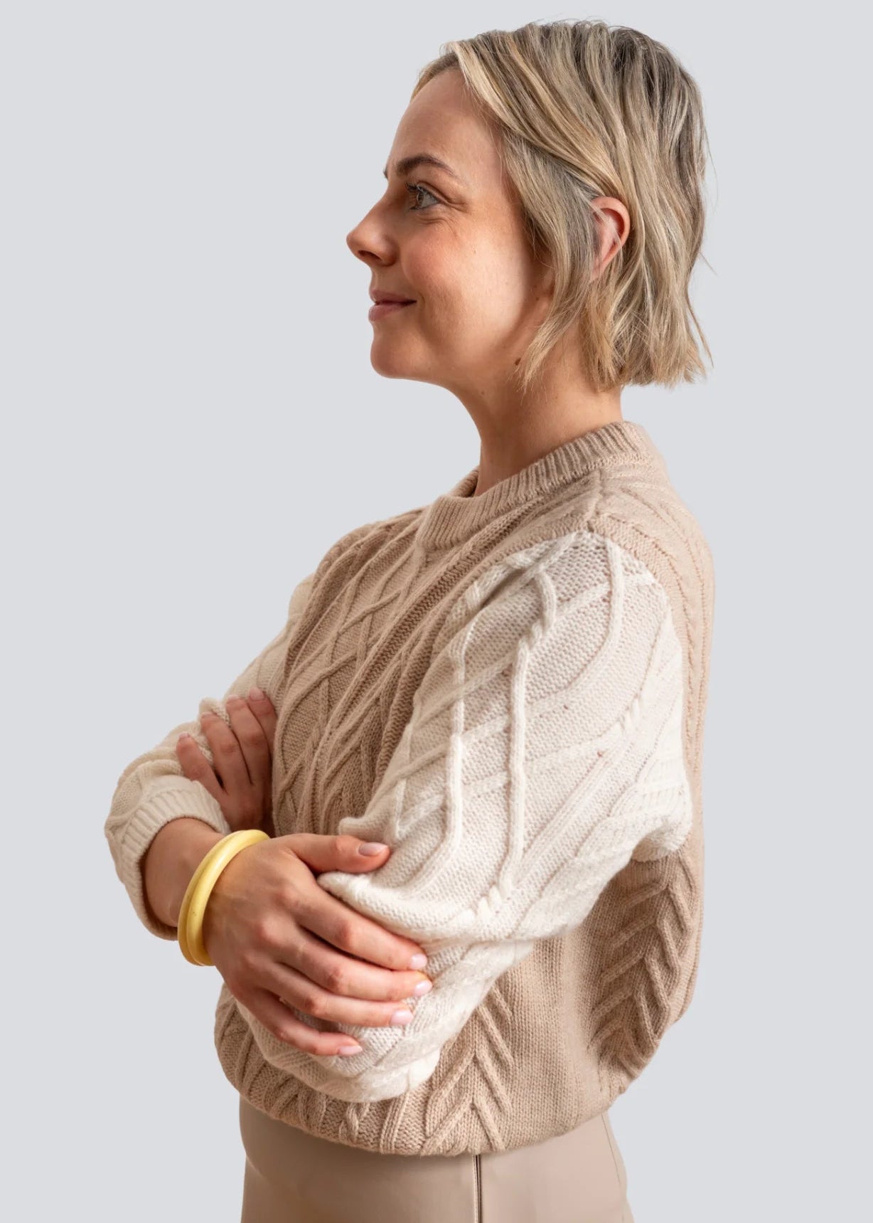 Woman wearing beige and white jumper on white background