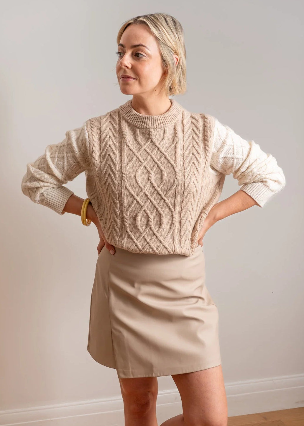 Woman wearing beige and white jumper on white background
