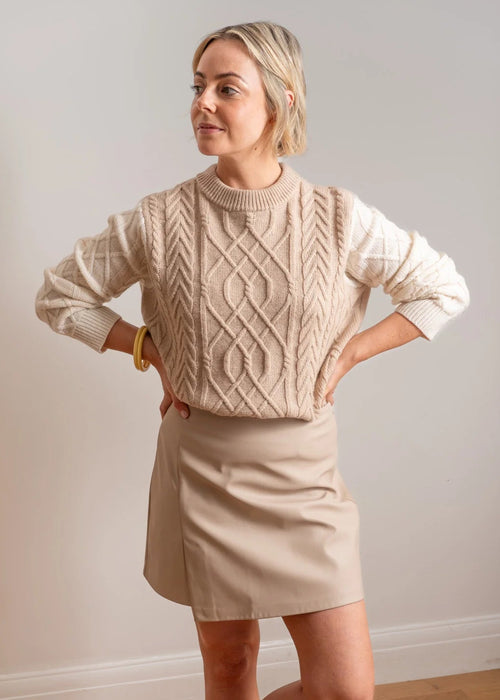 Woman wearing beige and white jumper on white background