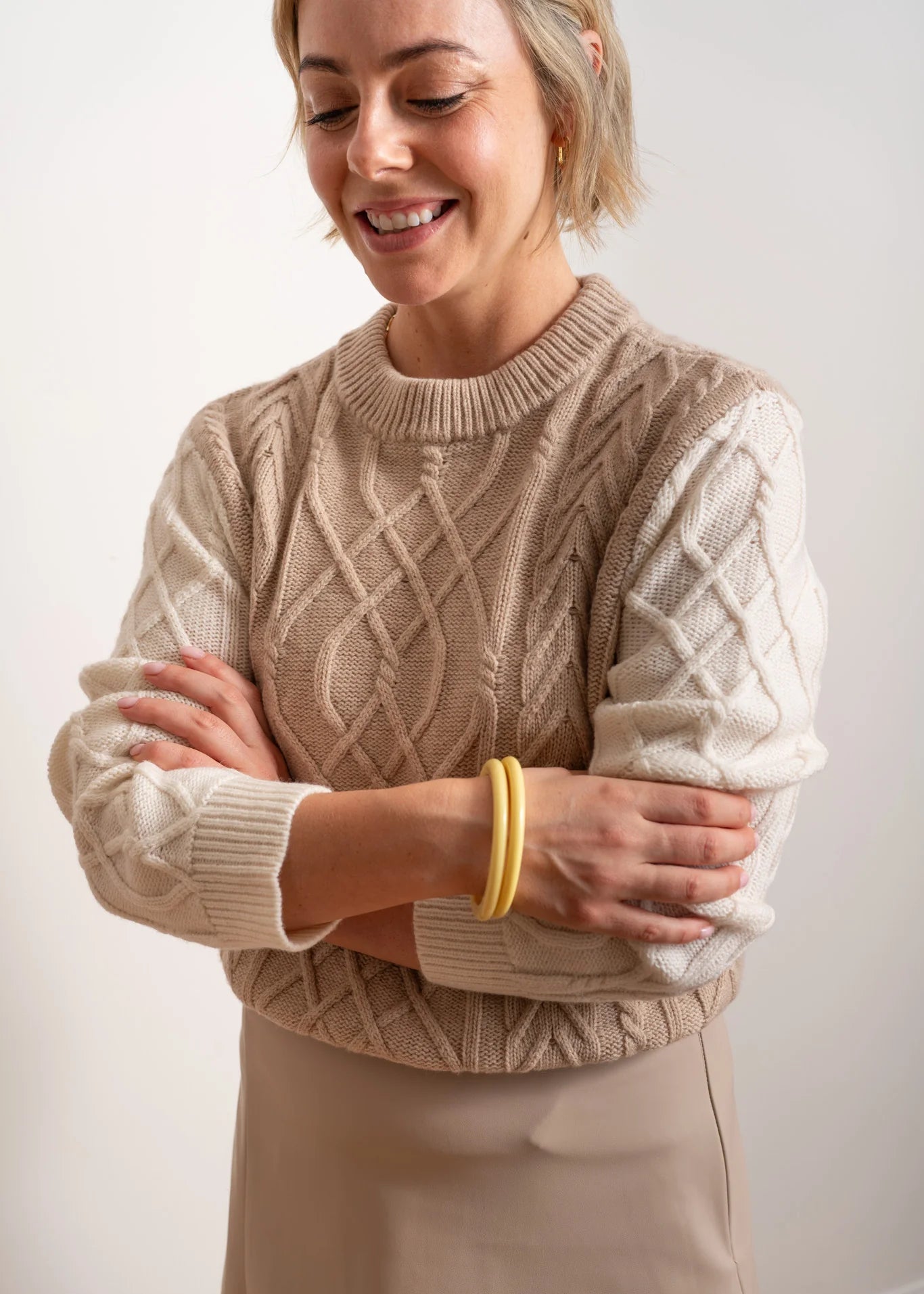 Woman wearing beige and white jumper on white background
