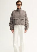 Person wearing a grey jacket and white pants on a white background