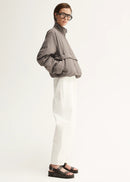 Person wearing a grey jacket and white pants on a white background