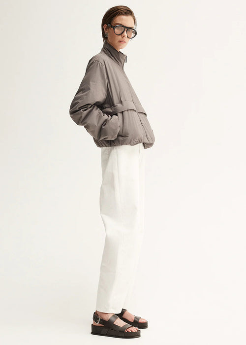 Person wearing a grey jacket and white pants on a white background