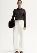 Woman wearing brown knit polo on white background
