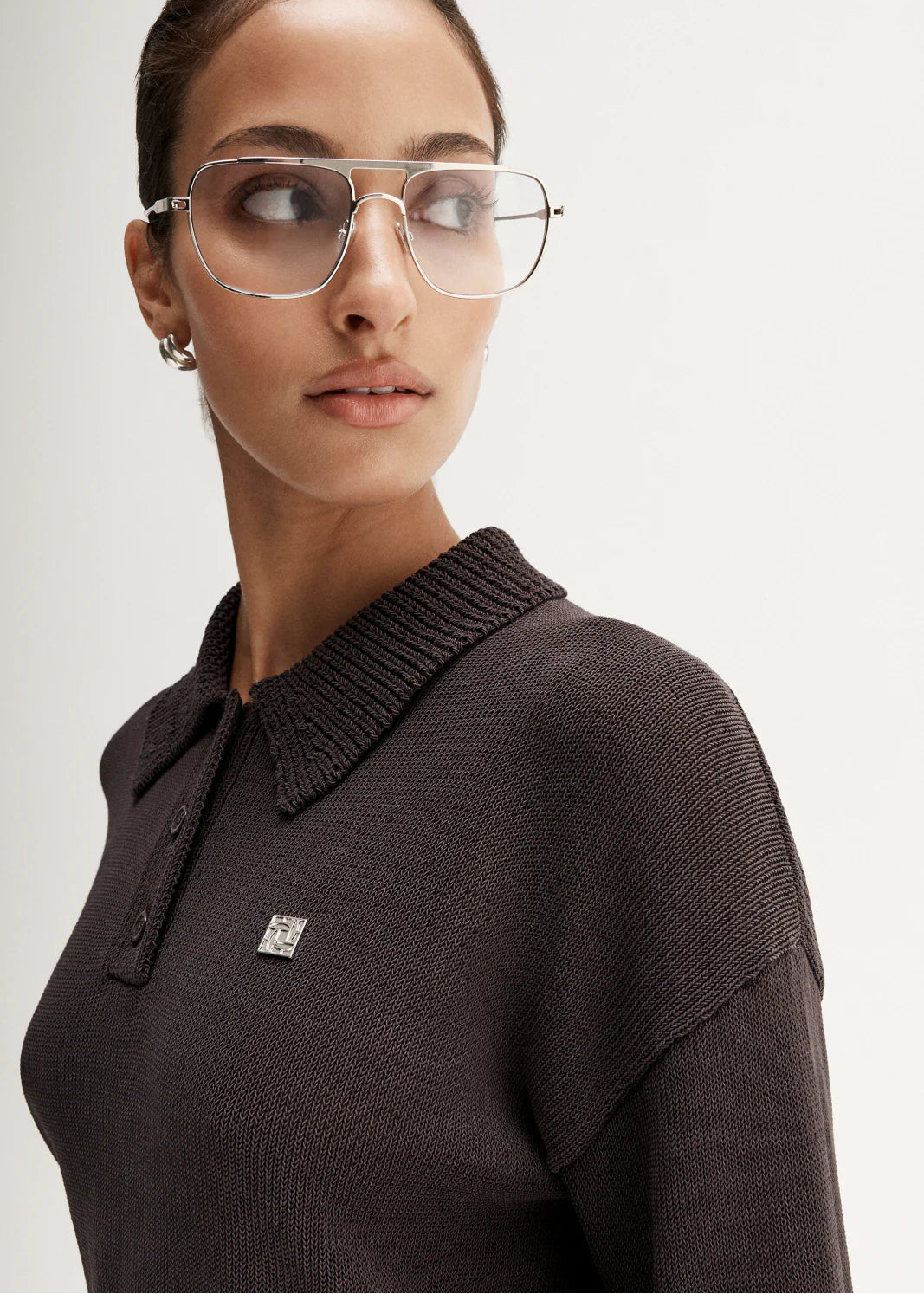 Woman wearing brown knit polo on white background