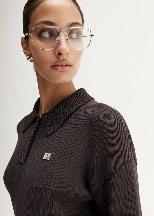 Woman wearing brown knit polo on white background