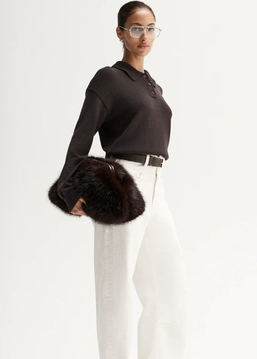 Woman wearing brown knit polo on white background