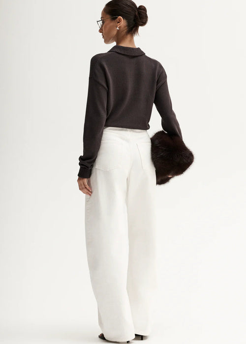 Woman wearing brown knit polo on white background