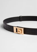 Black belt with a gold buckle on a light grey background