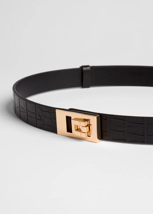 Black belt with a gold buckle on a light grey background