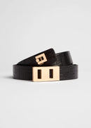 Black belt with a gold buckle on a light grey background