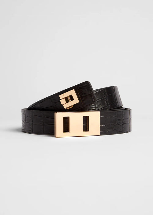 Black belt with a gold buckle on a light grey background