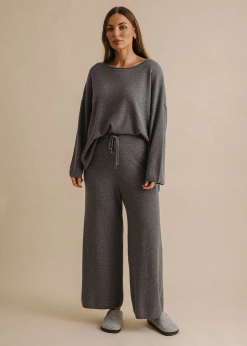 Person wearing grey sweatpants on a beige background