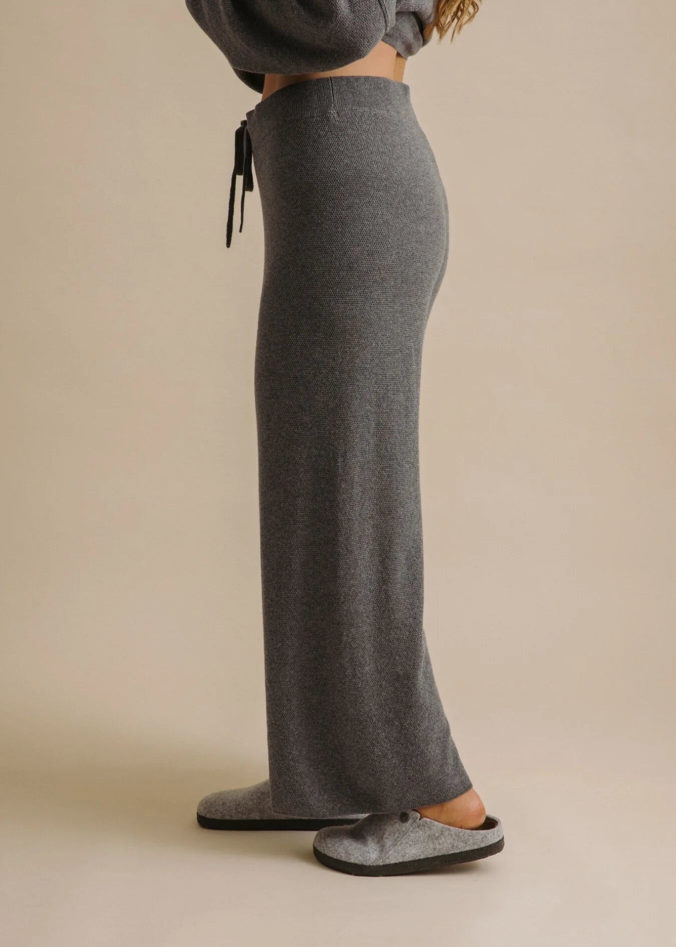 Person wearing grey sweatpants on a beige background