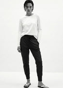Woman wearing a white top and black pants against a white background