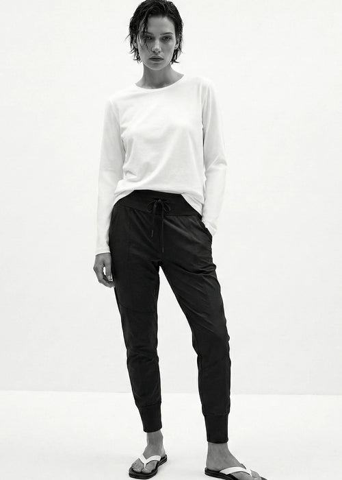 Woman wearing a white top and black pants against a white background