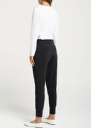 Woman wearing a white top and black pants against a white background