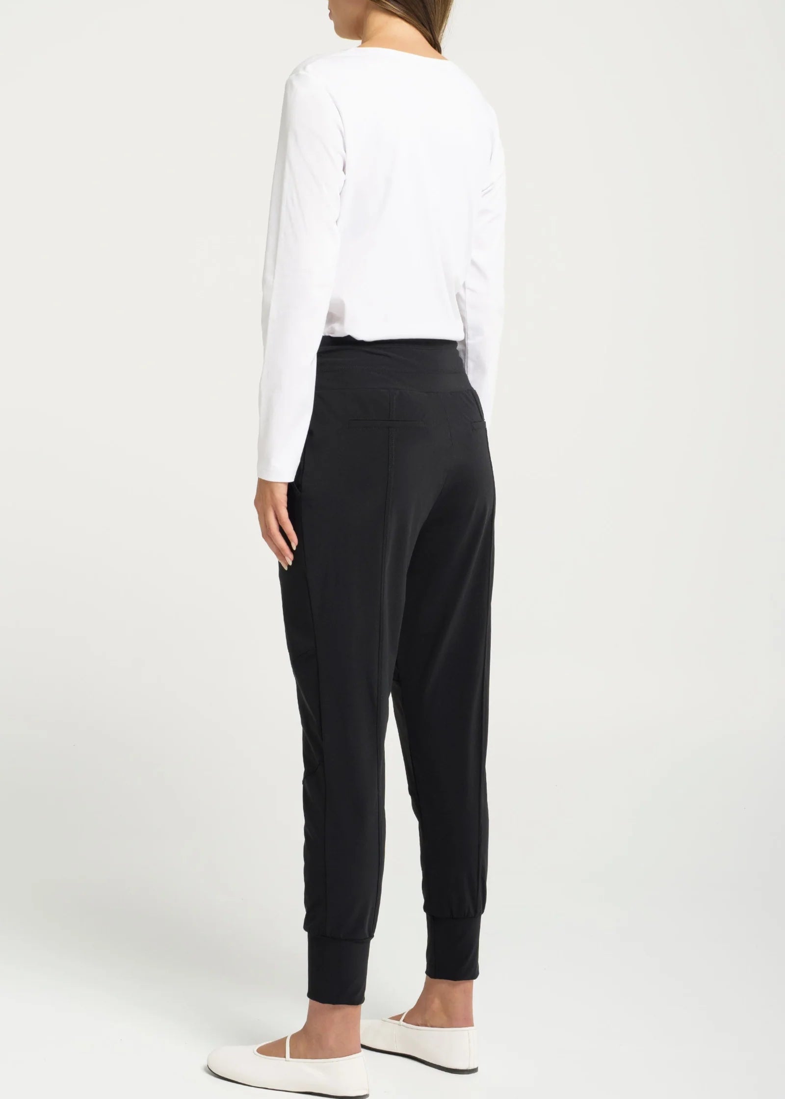 Woman wearing a white top and black pants against a white background
