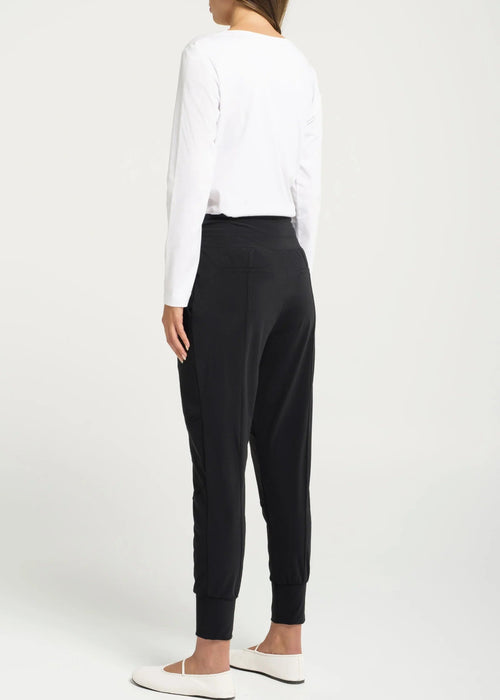 Woman wearing a white top and black pants against a white background