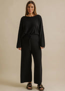 Woman wearing a black outfit on a beige background