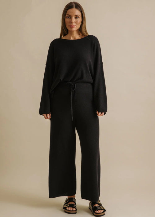 Woman wearing a black outfit on a beige background