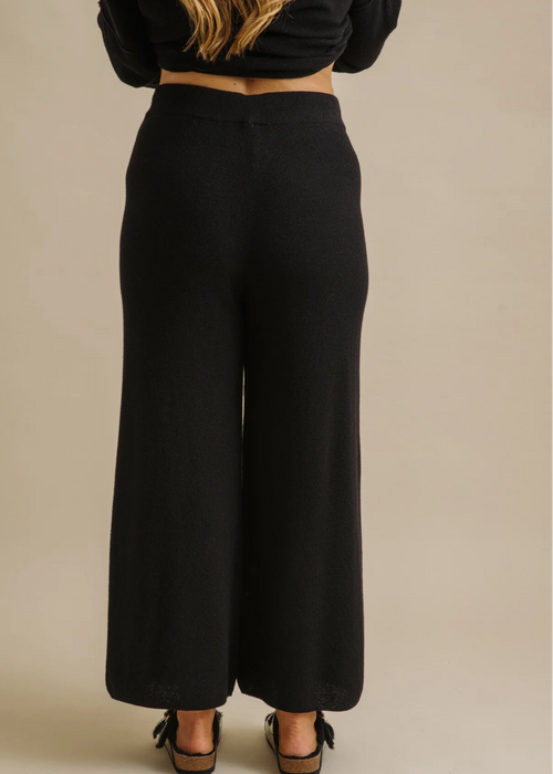 Woman wearing a black outfit on a beige background