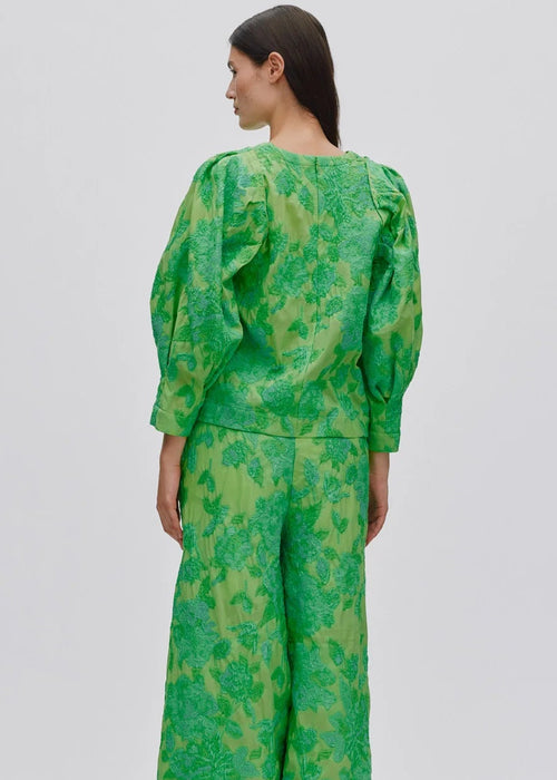 Person wearing a green patterned outfit on a light grey background