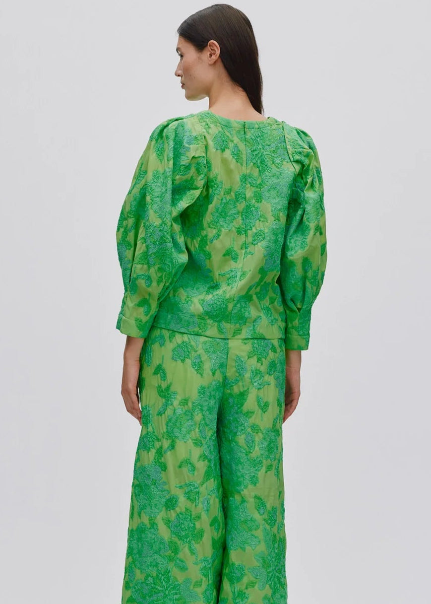 Person wearing a green patterned outfit on a light grey background