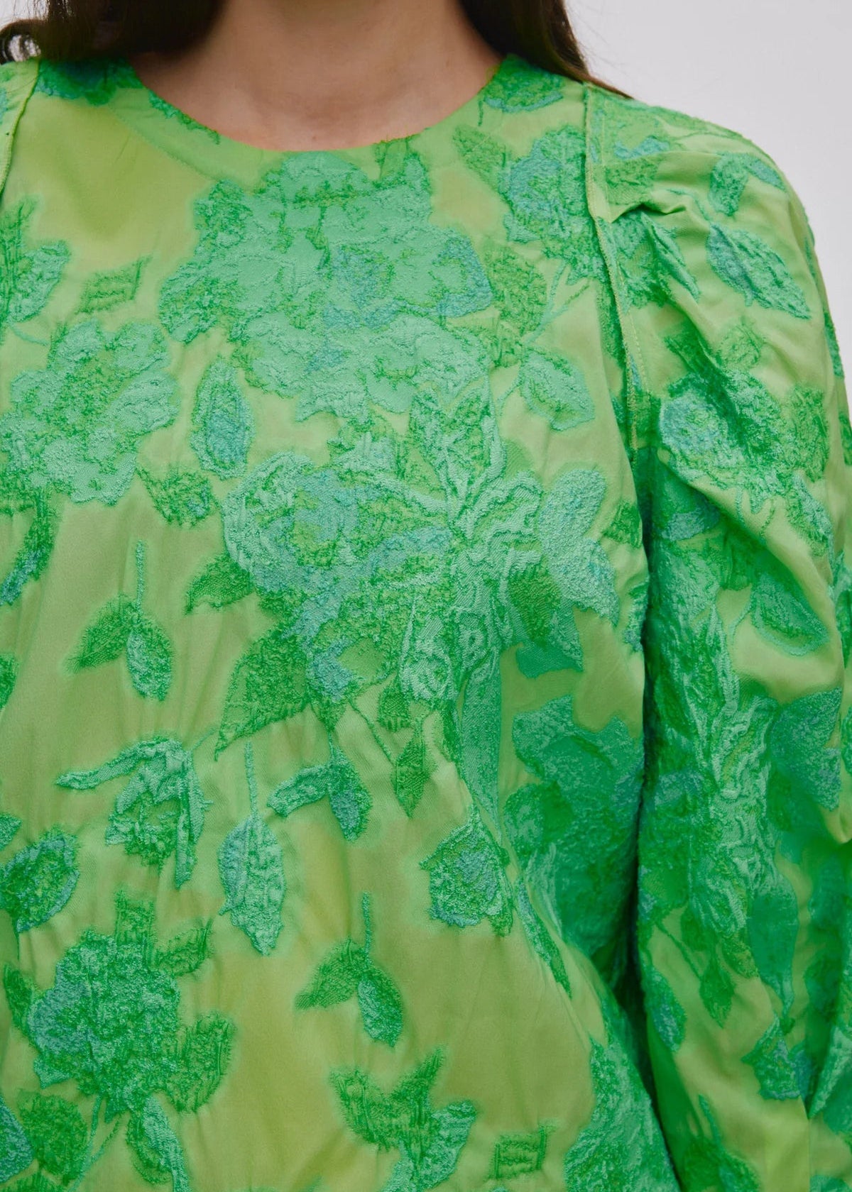 Person wearing a green patterned outfit on a light grey background