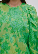 Person wearing a green patterned outfit on a light grey background