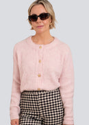 Woman wearing a pink cardigan and checkered pants with sunglasses on a light grey background