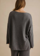 Woman wearing a grey pullover on a beige background