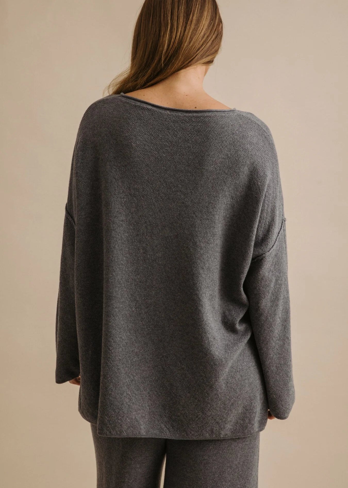 Woman wearing a grey pullover on a beige background
