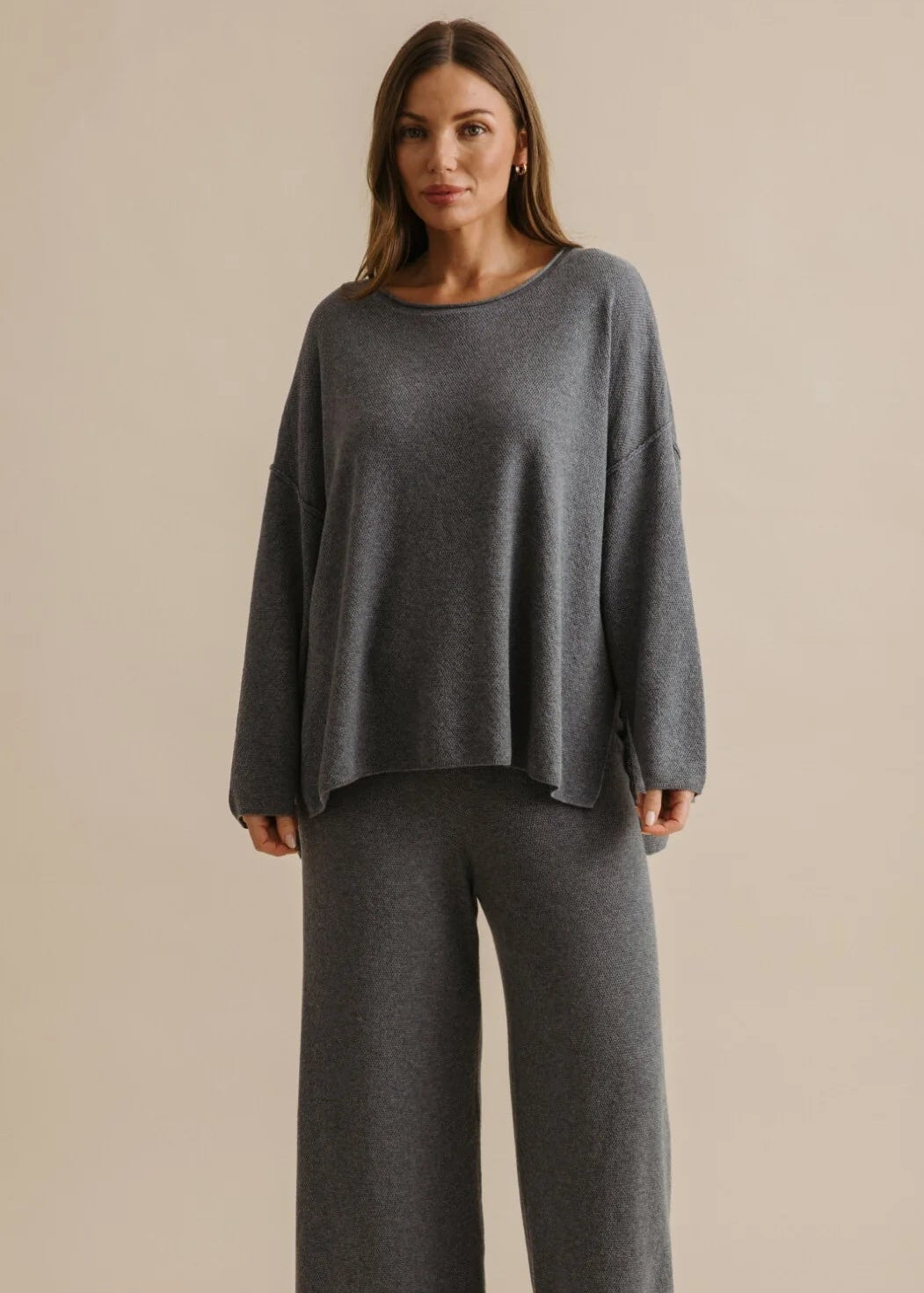 Woman wearing a grey pullover on a beige background