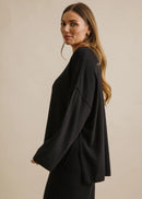 Woman wearing a black top and pants against a beige background