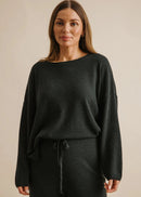 Woman wearing a dark green outfit against a beige background