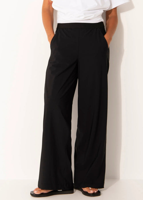 Person wearing black wide-leg pants and a white top on a white background