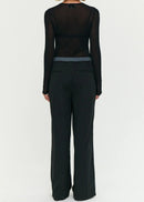 Model wearing a black outfit with sheer top and wide-leg pants on a white background