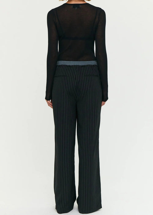 Model wearing a black outfit with sheer top and wide-leg pants on a white background